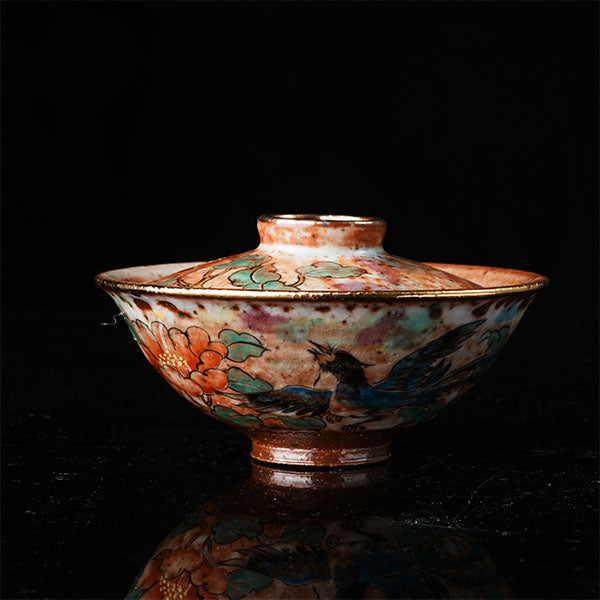 A traditional Chinese ceramic gaiwan with a lid, adorned with colorful floral and bird motifs. It features a golden rim, intricate hand-painted designs, and a glossy finish, embodying classic Chinese porcelain art. Ideal for tea ceremonies, this decorative piece showcases cultural heritage and fine craftsmanship. Perfect for collectors of Asian ceramics, highlighting vibrant colors and traditional aesthetics.