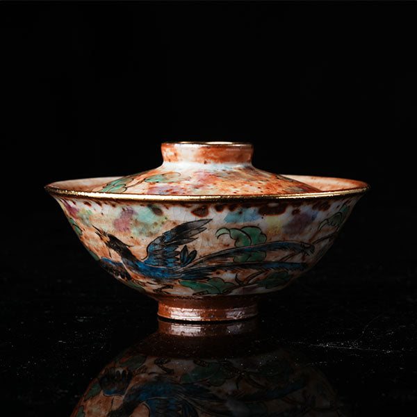 A traditional Chinese ceramic gaiwan with a lid, adorned with colorful floral and bird motifs. It features a golden rim, intricate hand-painted designs, and a glossy finish, embodying classic Chinese porcelain art. Ideal for tea ceremonies, this decorative piece showcases cultural heritage and fine craftsmanship. Perfect for collectors of Asian ceramics, highlighting vibrant colors and traditional aesthetics.