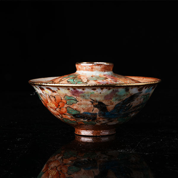 A traditional Chinese ceramic gaiwan with a lid, adorned with colorful floral and bird motifs. It features a golden rim, intricate hand-painted designs, and a glossy finish, embodying classic Chinese porcelain art. Ideal for tea ceremonies, this decorative piece showcases cultural heritage and fine craftsmanship. Perfect for collectors of Asian ceramics, highlighting vibrant colors and traditional aesthetics.