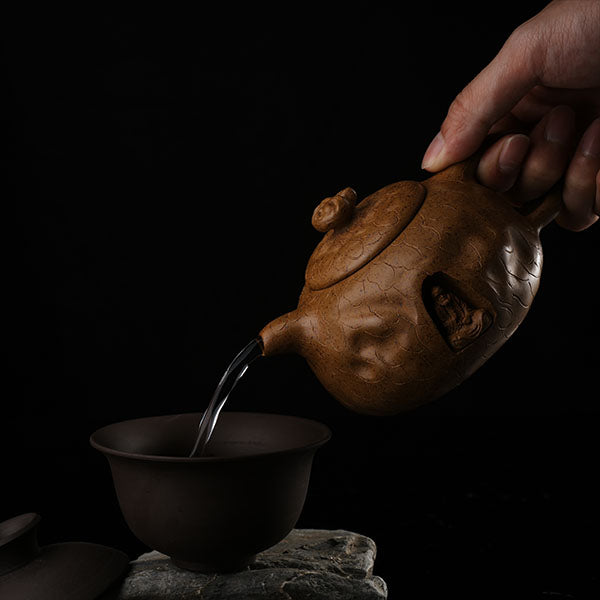 This is Gulong Klin Bodhidharma Gongchun Purple Clay Teapot, Handcrafted Zen-inspired teapot for tea rituals.The purple clay teapot is mainly khaki in color, and a Bodhidharma figure is engraved on the outer wall.