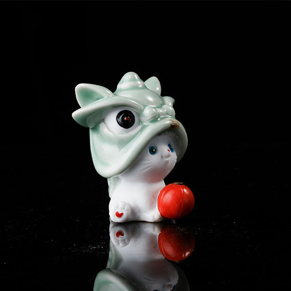 This is a lucky cat tea pet wearing a lion dance hat.