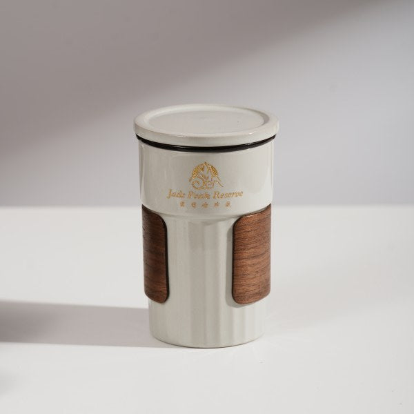 This is a branded teacup with accessories including a teacup with a lid and a filter pot in the teacup. The brand is Jade Peak Reserve. There is a wooden anti-scalding plate on one side of the cup and a cute panda on the other side.