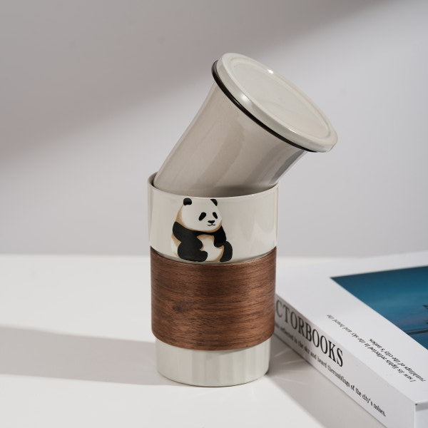 This is a branded teacup with accessories including a teacup with a lid and a filter pot in the teacup. The brand is Jade Peak Reserve. There is a wooden anti-scalding plate on one side of the cup and a cute panda on the other side.