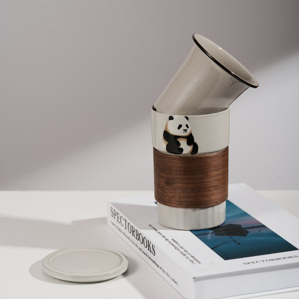 This is a branded teacup with accessories including a teacup with a lid and a filter pot in the teacup. The brand is Jade Peak Reserve. There is a wooden anti-scalding plate on one side of the cup and a cute panda on the other side.