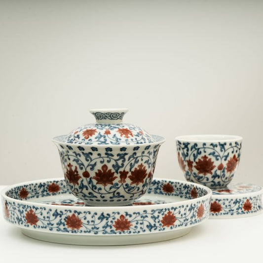 The Gaiwan has a white base with blue patterns in a ring shape surrounding red flowers.