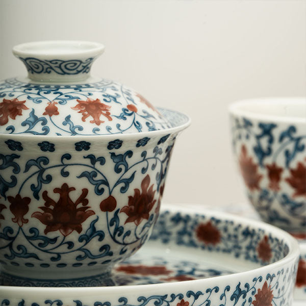 The Gaiwan has a white base with blue patterns in a ring shape surrounding red flowers.