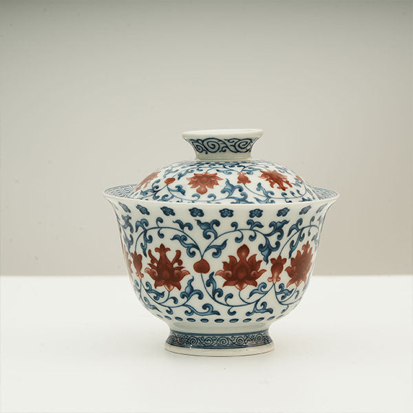 The Gaiwan has a white base with blue patterns in a ring shape surrounding red flowers.