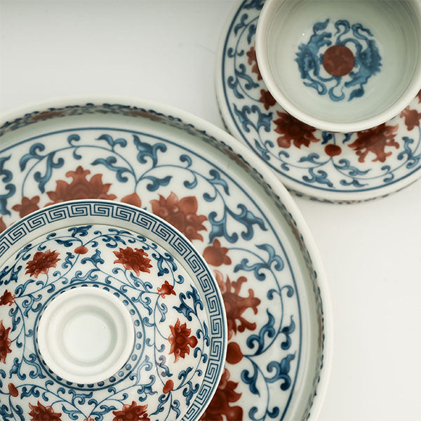 The Gaiwan has a white base with blue patterns in a ring shape surrounding red flowers.
