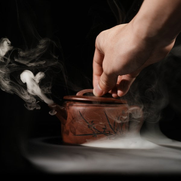 This is a handmade Yixing purple clay teapot, made by Master Chen Xiaozhong. There are bamboo leaves carved on the left side of the teapot, and the four characters "Hou De Zai Wu" are written on the right side.