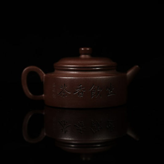 This purple clay teapot is dark brown in color, with a Chinese garden landscape of a small bridge and flowing water painted on the left side of the teapot, and the words "Sitting and Drinking Tea" engraved on the right side. This purple clay teapot was made by Chinese purple clay teapot master Chen Xiaozhong and was produced in Yixing, a famous purple clay teapot production area in China.