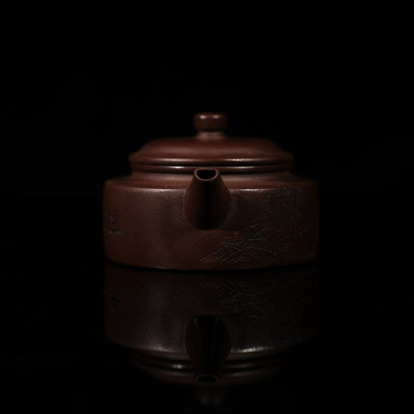 This purple clay teapot is dark brown in color, with a Chinese garden landscape of a small bridge and flowing water painted on the left side of the teapot, and the words "Sitting and Drinking Tea" engraved on the right side. This purple clay teapot was made by Chinese purple clay teapot master Chen Xiaozhong and was produced in Yixing, a famous purple clay teapot production area in China.