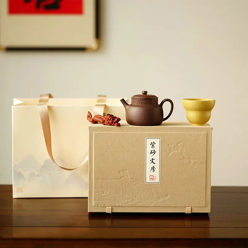 A teapot, a cup, and a tea pet gift box from Jiquan.