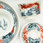 The Gaiwan has a white base with blue and white wave patterns on it, and a red Chinese loong is flying above the waves.