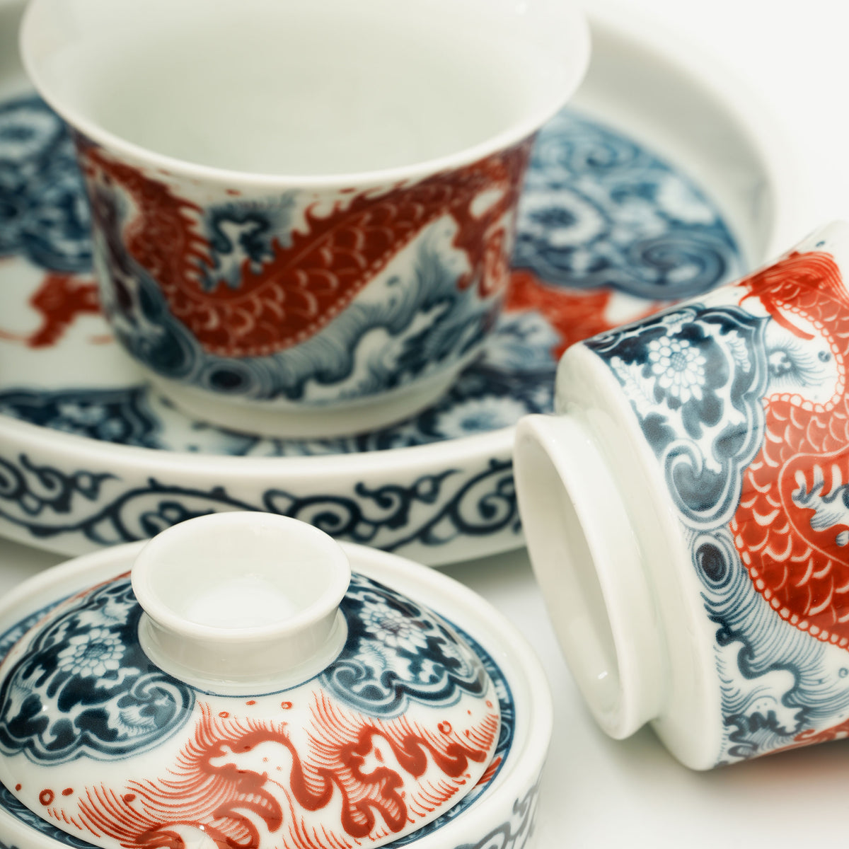 The Gaiwan has a white base with blue and white wave patterns on it, and a red Chinese loong is flying above the waves.