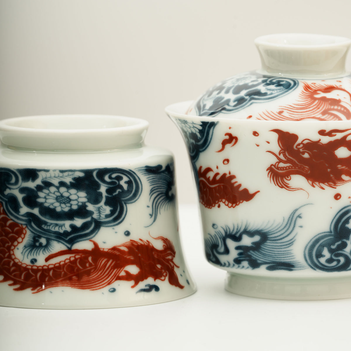 The Gaiwan has a white base with blue and white wave patterns on it, and a red Chinese loong is flying above the waves.