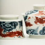 The Gaiwan has a white base with blue and white wave patterns on it, and a red Chinese loong is flying above the waves.