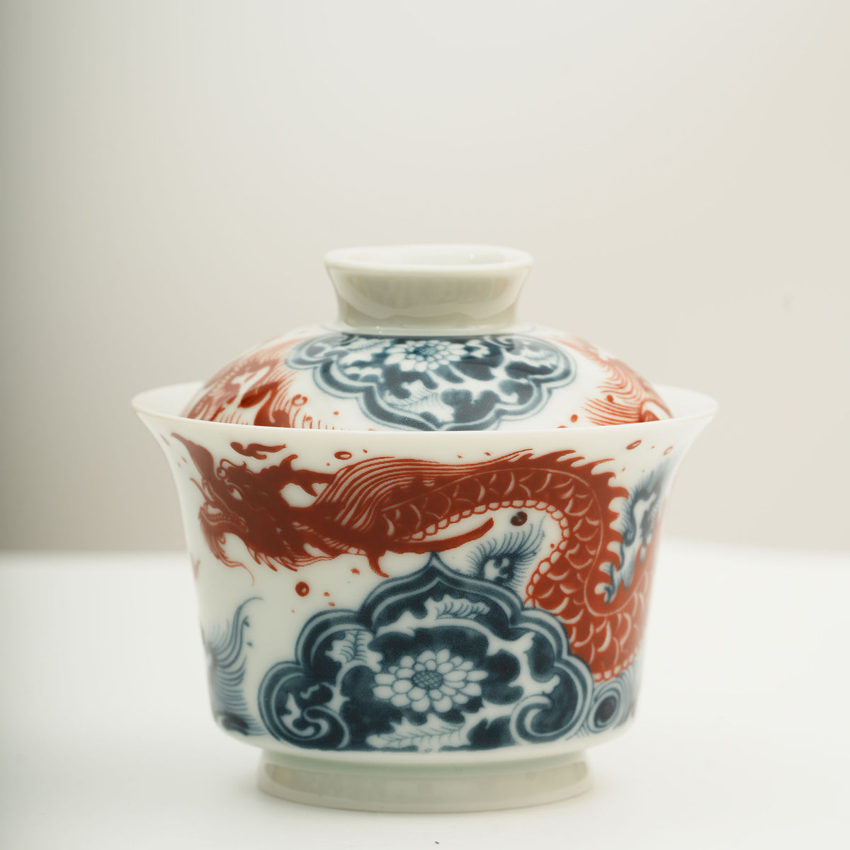 The Gaiwan has a white base with blue and white wave patterns on it, and a red Chinese loong is flying above the waves.