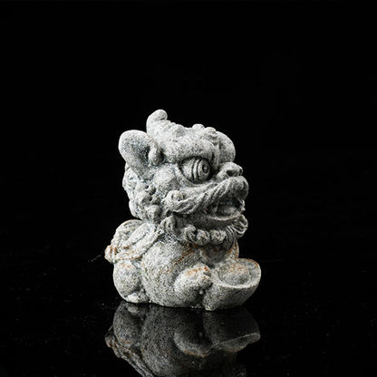 This is a lion dance tea pet holding a gold ingot.
