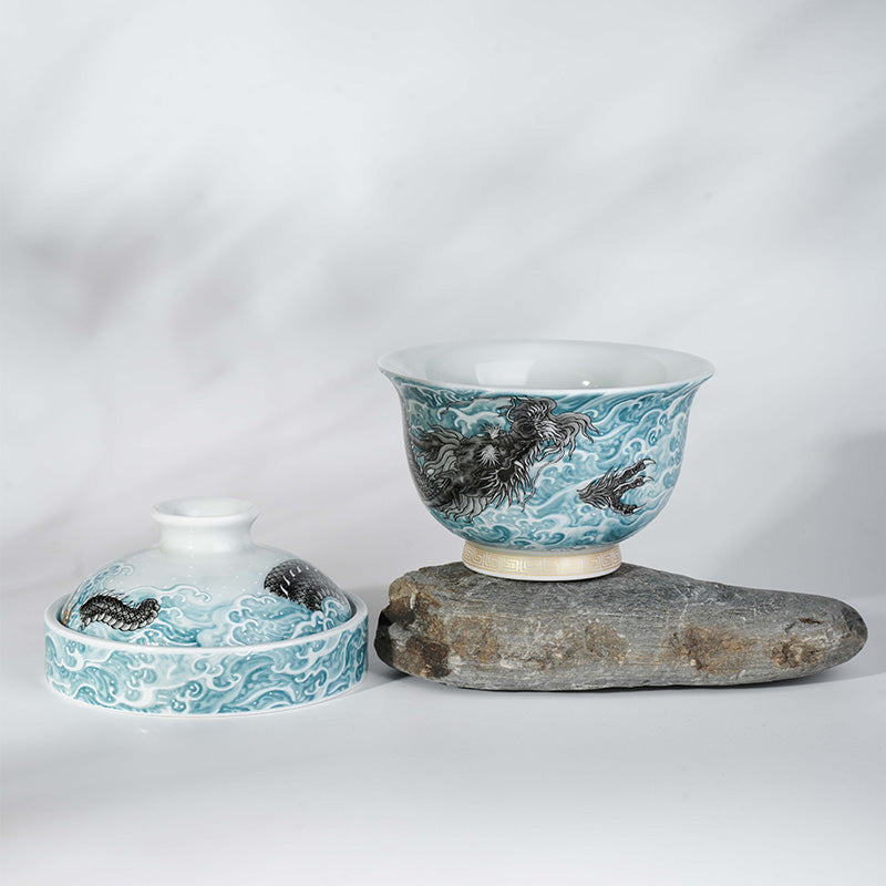 This showcases an exquisite blue and white gaiwan with a lifelike loong pattern. The bowl is placed on an irregular gray stone base with a light background, creating a classic and elegant atmosphere.