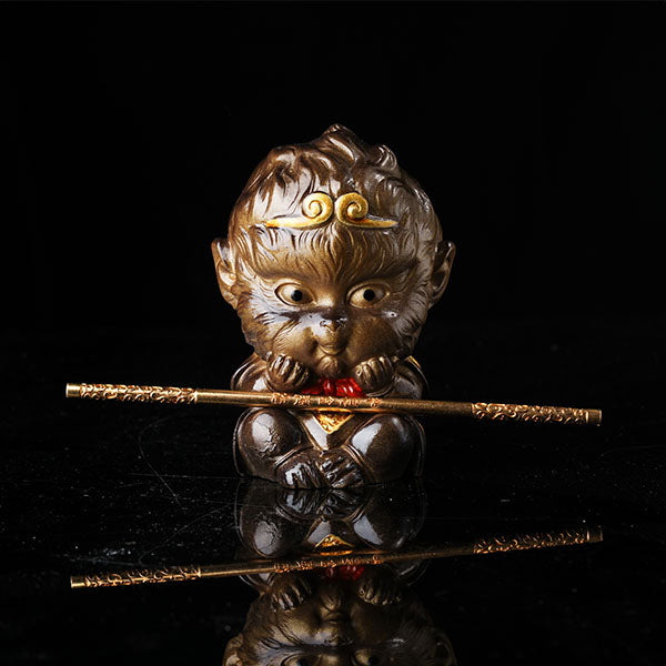 This is the Son Wukong tea pet sitting cross-legged on the ground, holding the golden hoop stick.