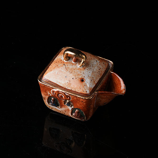 The Buddha without Form Square Teapot - Traditional ceramic teapot with square form, speckled brown glaze, gold handle, and relief figures (possibly Buddhist motifs). Handcrafted, rustic design, ideal for tea rituals. Features intricate detailing, cultural artistry, and functional elegance. Perfect for collectors of unique teaware, highlighting craftsmanship and traditional aesthetics.