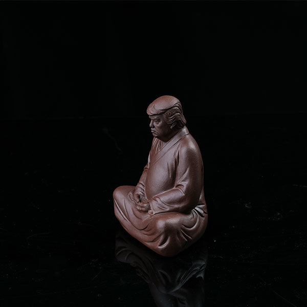 This is a purple clay tea pet with the image of Trump.
