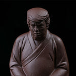 This is a purple clay tea pet with the image of Trump.