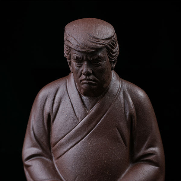 This is a purple clay tea pet with the image of Trump.