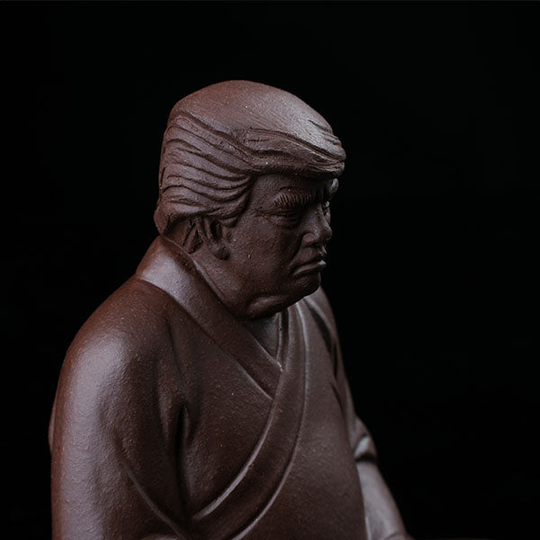 This is a purple clay tea pet with the image of Trump.