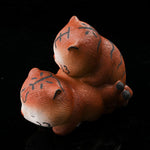 This is a purple clay tea pet with two little tigers hugging and sleeping.