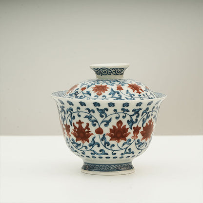 The Gaiwan has a white base with blue patterns in a ring shape surrounding red flowers.